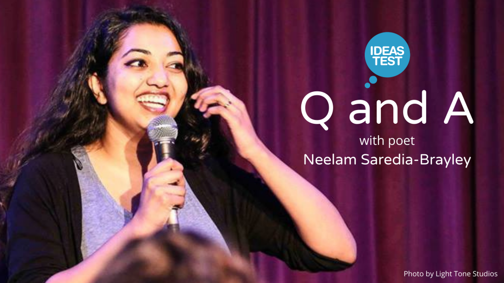 Photo of poet Neelam Saredia-Brayley. Neelam is a young woman who is standing in front of a stage curtain in front of an audience. She is holding a microphone and smiling.
