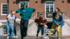 4 dancers in colourful clothes are outdoors, captured moving expressively.