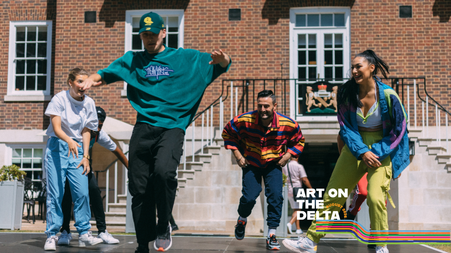 4 dancers in colourful clothes are outdoors, captured moving expressively.